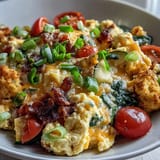 Fluffy scrambled eggs and vibrant red bell peppers in a Scrambled Egg and Veggie Bowl, topped with gooey melted cheese.