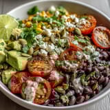 Vibrant Black Bean and Veggie Bowl topped with creamy avocado, corn, and tomatoes in a zesty lime dressing.