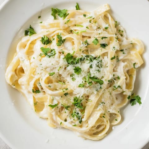 Tender sliced chicken breast rests atop a warm, steaming bowl of Fettuccine Alfredo.
