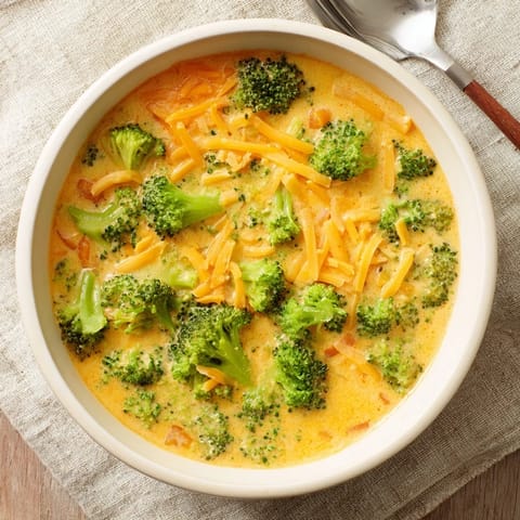Steaming bowl of homemade Broccoli Cheese Soup with tender broccoli florets and melted cheddar.