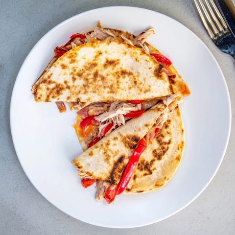 Freshly cooked Chicken Quesadilla with grilled chicken and peppers, served with sour cream and salsa dip.