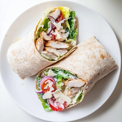 Chicken Caesar Wrap cut in half to reveal creamy Caesar dressing and fresh romaine lettuce inside a soft wheat tortilla.