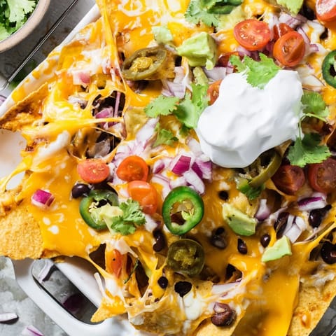 Loaded nachos recipe featuring seasoned ground beef, spicy peppers, and fresh tomatoes ready to share.