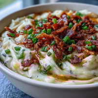 Creamy Loaded Potato Soup topped with crispy bacon, melted cheddar, and fresh green onions in a rustic bowl.