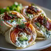 Smoked salmon and cucumber cream cheese pinwheels with dill, rolled in soft tortillas for a refreshing appetizer.  